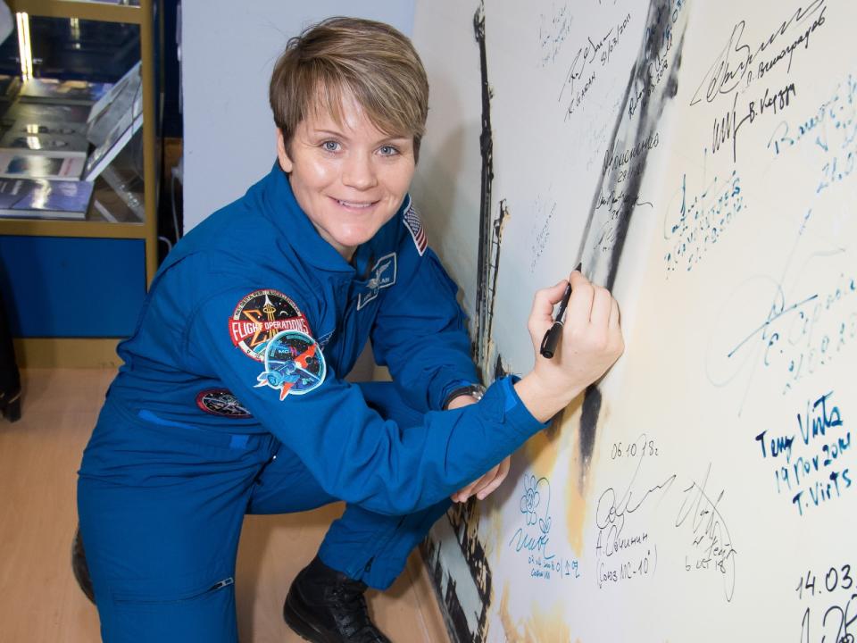 NASA astronaut Anne McClain signed a wall at the Baikonur Cosmodrome Museum in Kazakhstan on Nov. 29, a traditional task for astronauts pre-launch. <cite>Victor Zelentosov/NASA</cite>